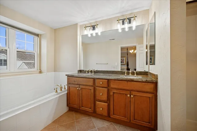 a bathroom with a granite countertop bathtub a double vanity sink and mirror