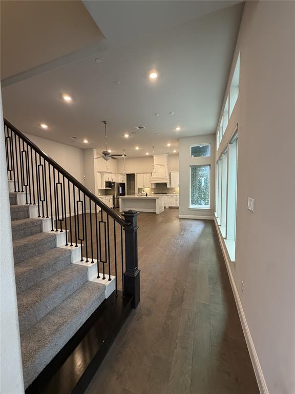 1049 Sarah Street Allen, TX 75013 - Photo 2 of 12 Carpeted staircase with black iron balusters and a dark wood newel post