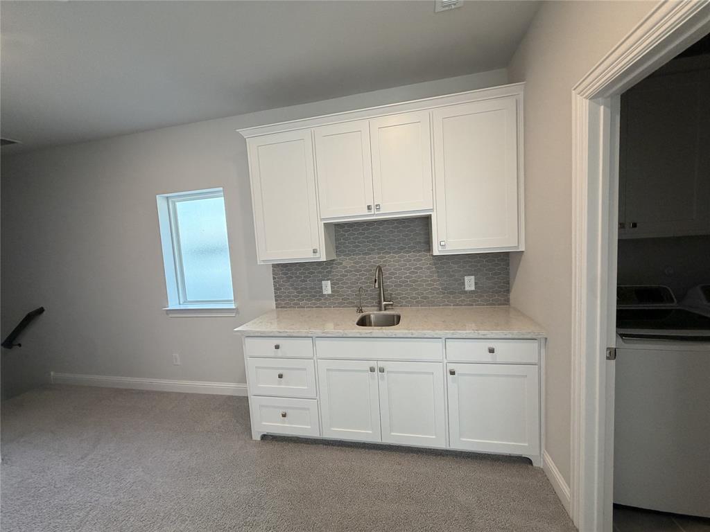 1049 Sarah Street Allen, TX 75013 - Photo 7 of 12 Built-in wet bar featuring white shaker-style cabinetry, a stainless steel sink with a gooseneck faucet, a light-colored countertop, and a gray geometric tile backsplash
