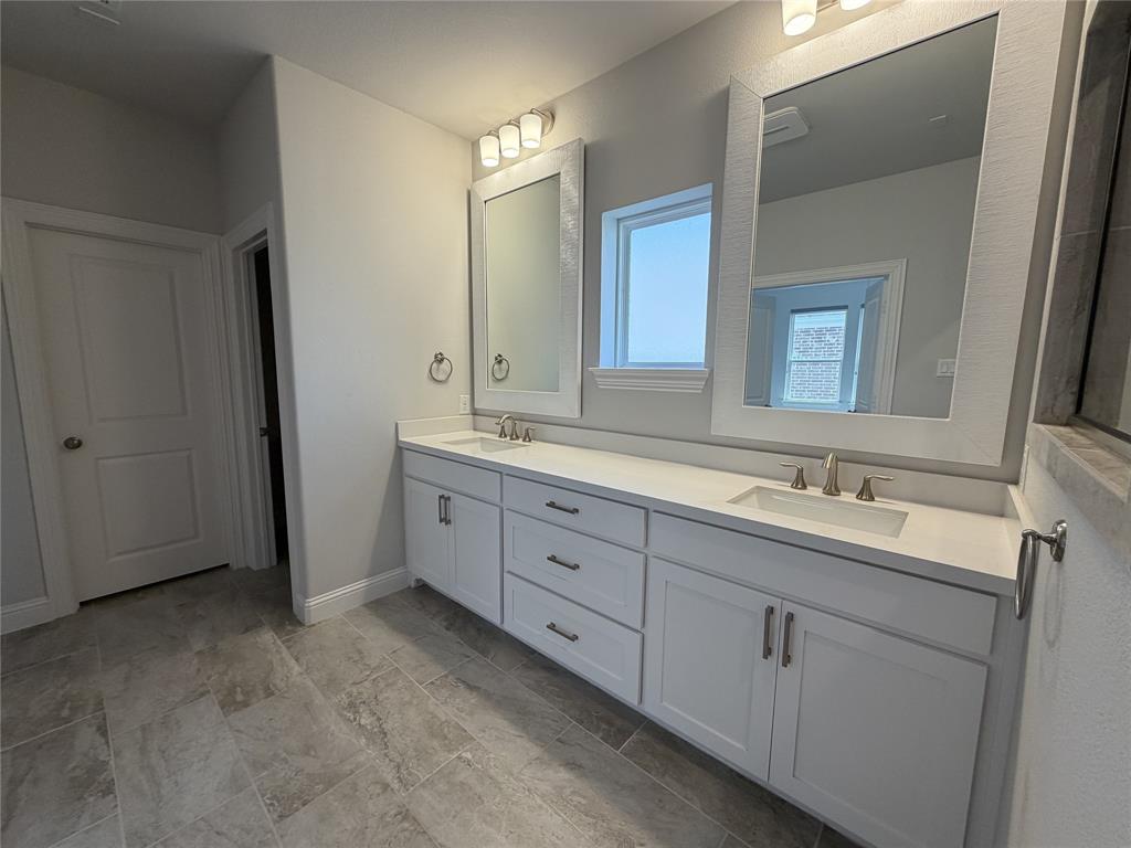 1049 Sarah Street Allen, TX 75013 - Photo 8 of 12 Dual vanity featuring white shaker-style cabinetry, undermount sinks, and light-toned countertops