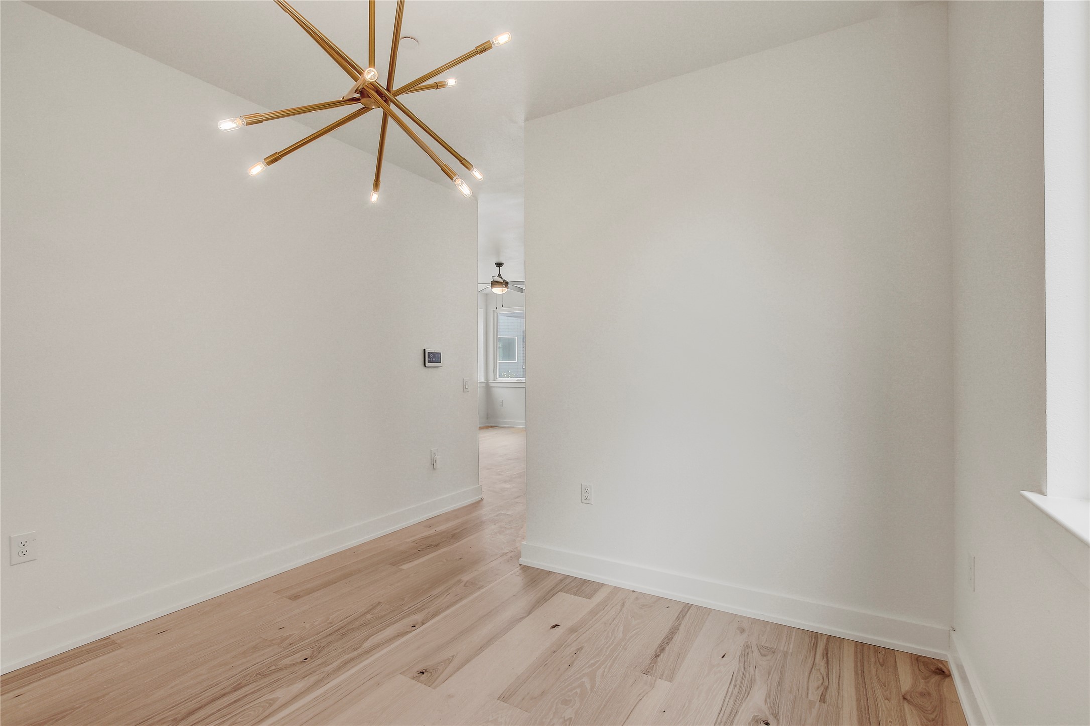 4127 East 12th Street, Unit 2 Austin, TX 78721 - Photo 14 of 28 Empty room featuring a chandelier, light wood-type flooring, and baseboards