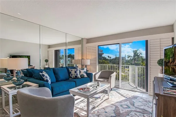 a living room with furniture a flat screen tv and a floor to ceiling window