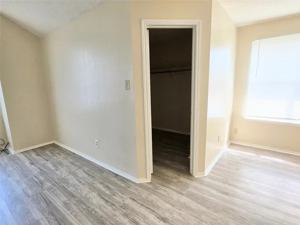 an empty room with wooden floor & closet area