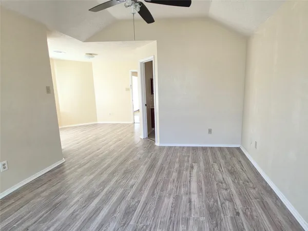 a view of a room with wooden floor a ceiling fan and window