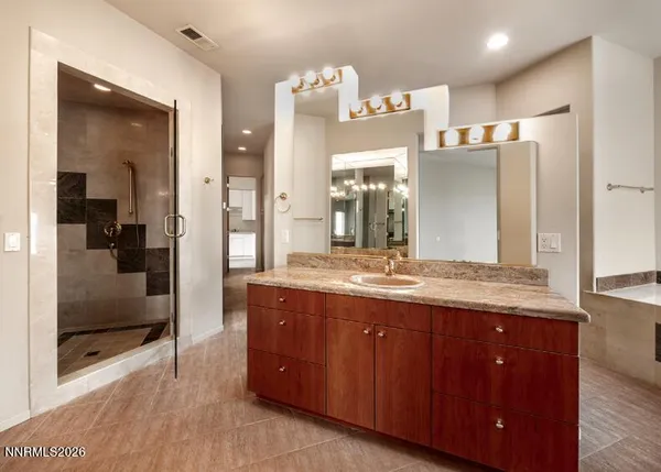 a bathroom with a granite countertop sink a large mirror and a shower