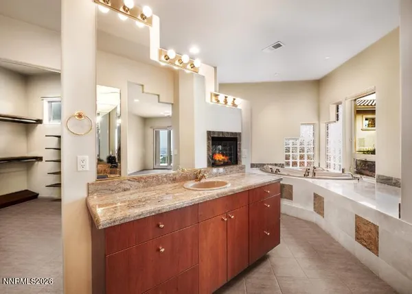 a spacious bathroom with a granite countertop double vanity sink a large mirror and a bathtub