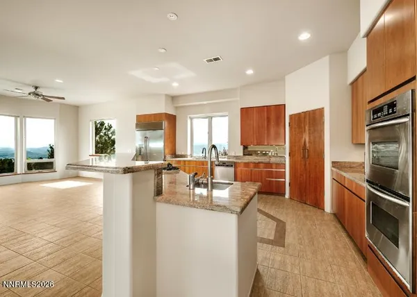 a kitchen with stainless steel appliances granite countertop a refrigerator a stove and a sink with wooden floor