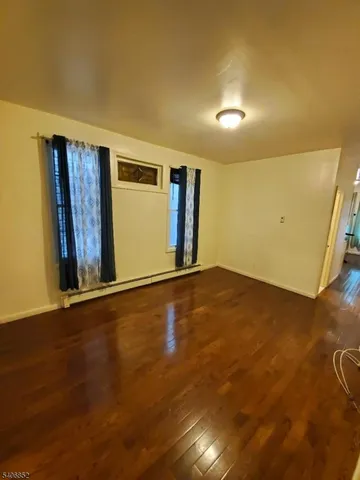 a view of an empty room with wooden floor and window