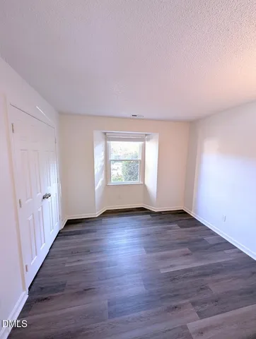 a view of an empty room with wooden floor and window