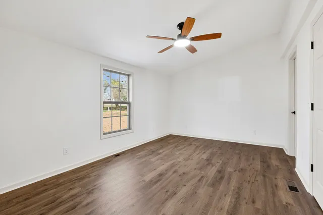 an empty room with wooden floor and a ceiling fan