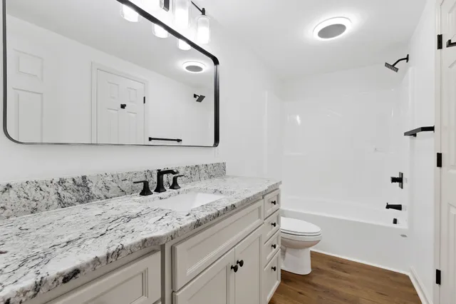a bathroom with a granite countertop sink a toilet and shower
