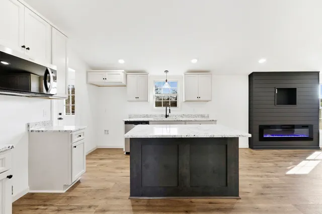 a large white kitchen with stainless steel appliances granite countertop a lot of counter space and wooden floors