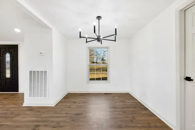 an empty room with wooden floor closet and windows