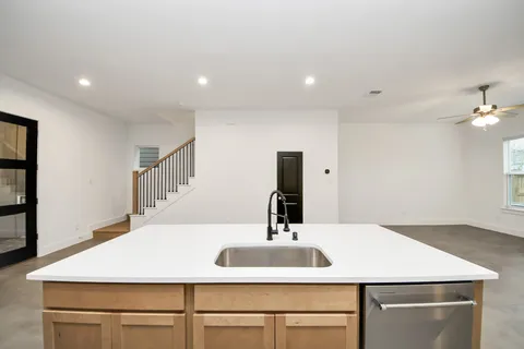 an empty room with chandelier fan and windows