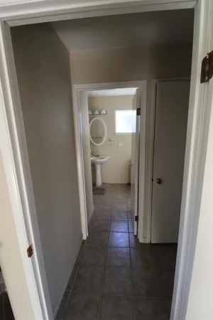 a view of a hallway with a glass door and a bathroom space