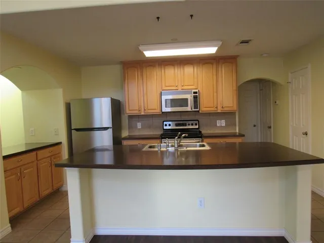 a kitchen with kitchen island a counter top space cabinets and stainless steel appliances