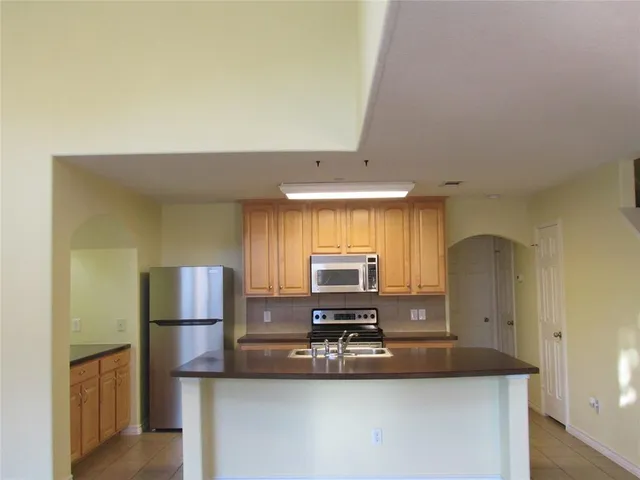 a view of a kitchen with kitchen island a sink appliances and a counter top space