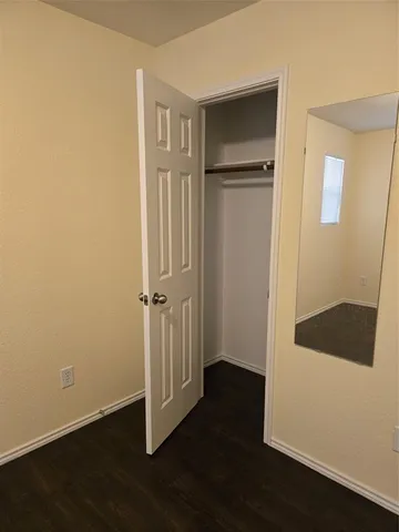 an empty room with wooden floor door and windows