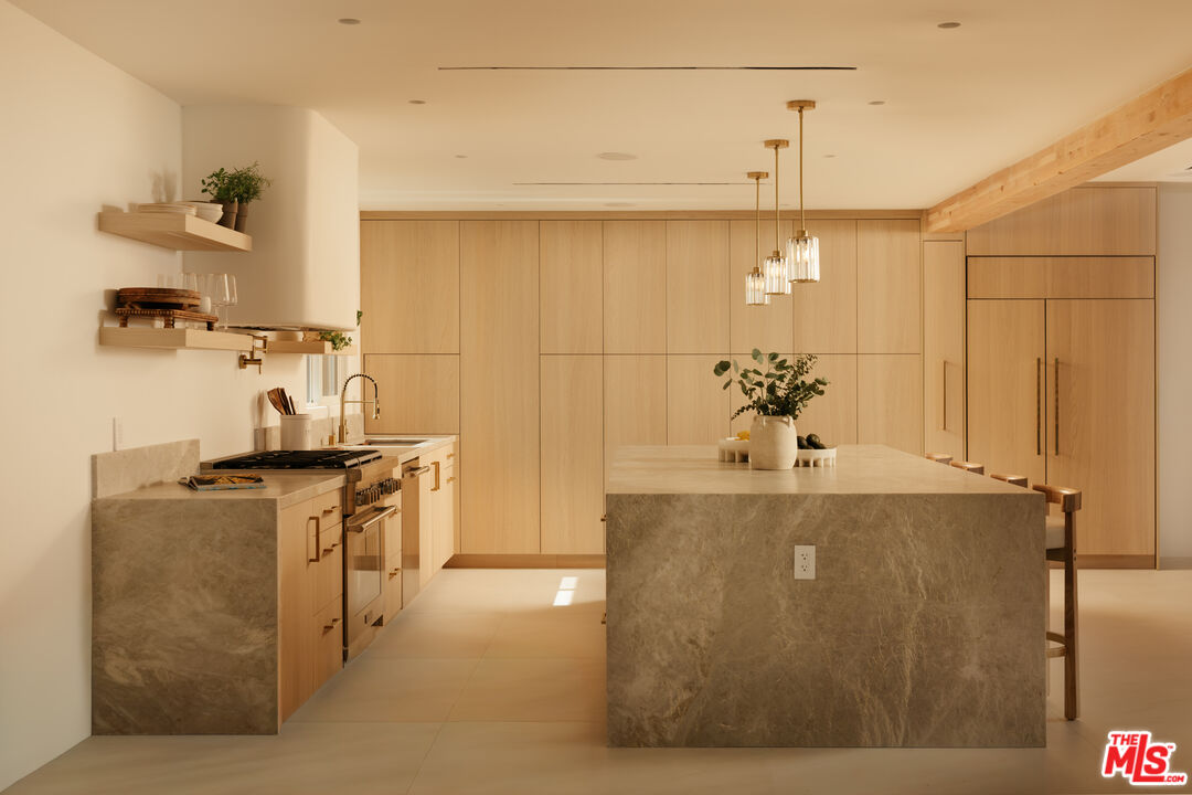 880 Teakwood Road Los Angeles, CA 90049 - Photo 11 of 38 a view of a kitchen with kitchen island a counter top space stove and cabinets