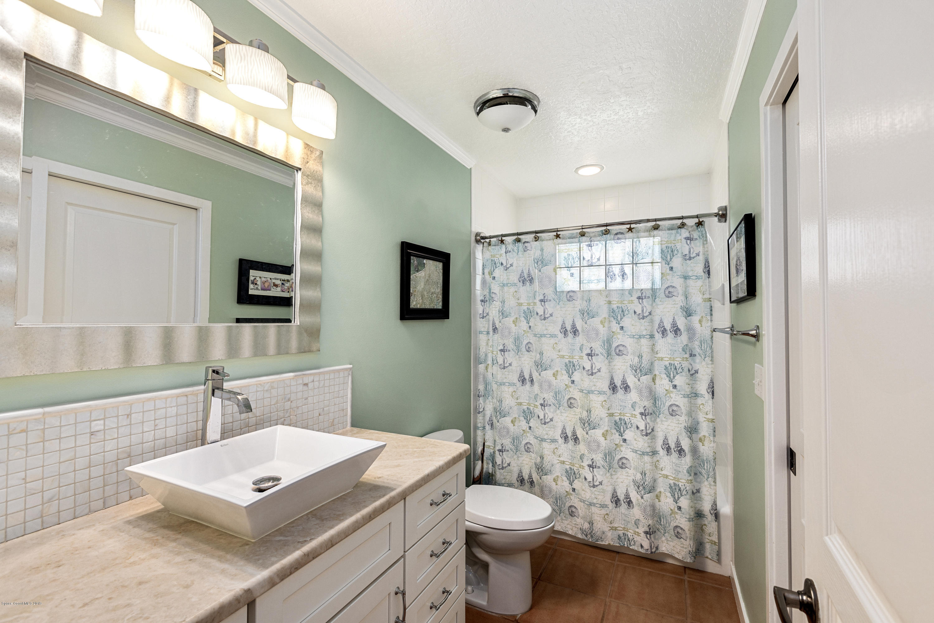 4231 Turtle Mound Road Melbourne, FL 32934 - Photo 16 of 39 a bathroom with a sink toilet a mirror and shower