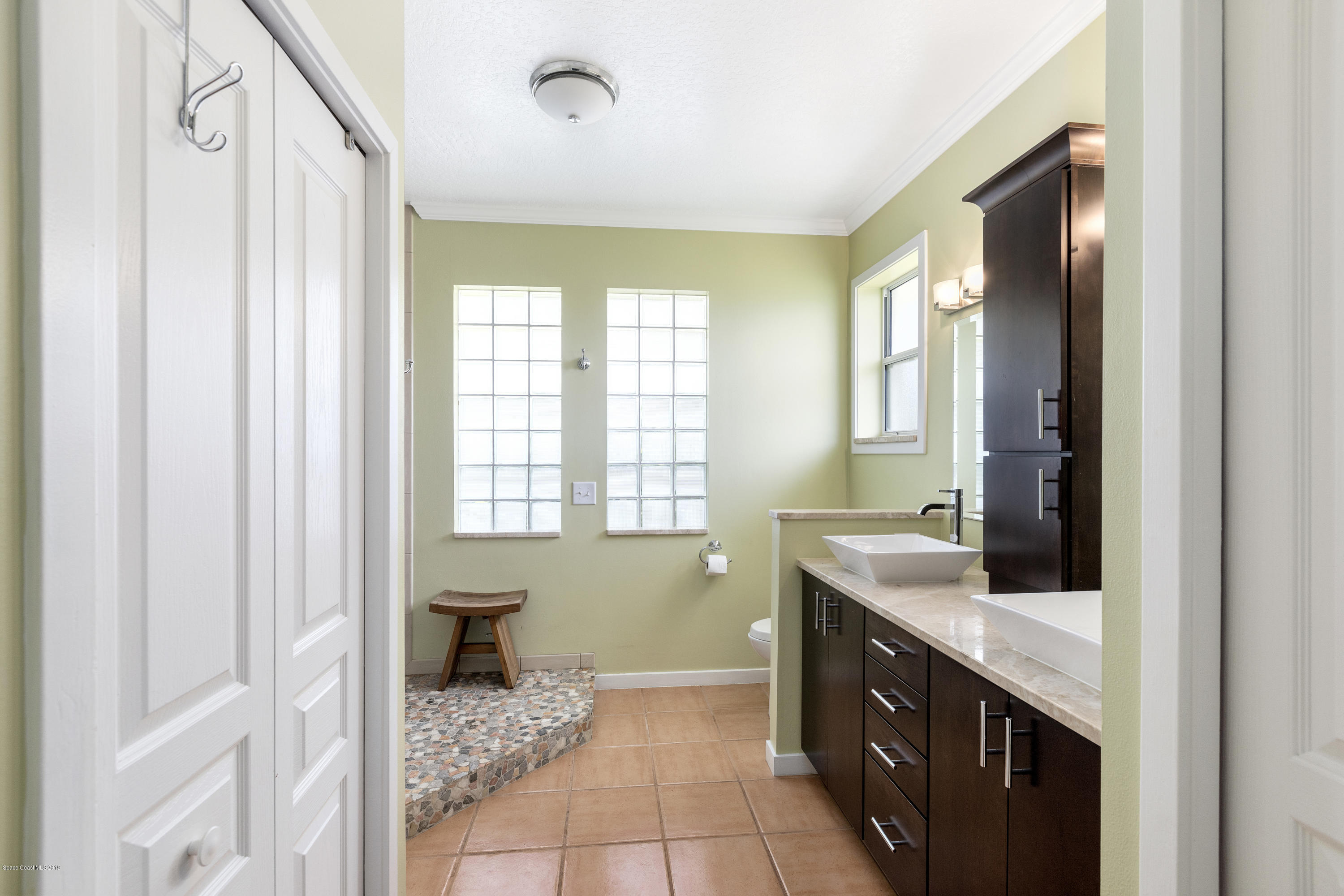 4231 Turtle Mound Road Melbourne, FL 32934 - Photo 20 of 39 a bathroom with a double vanity sink a toilet and a mirror
