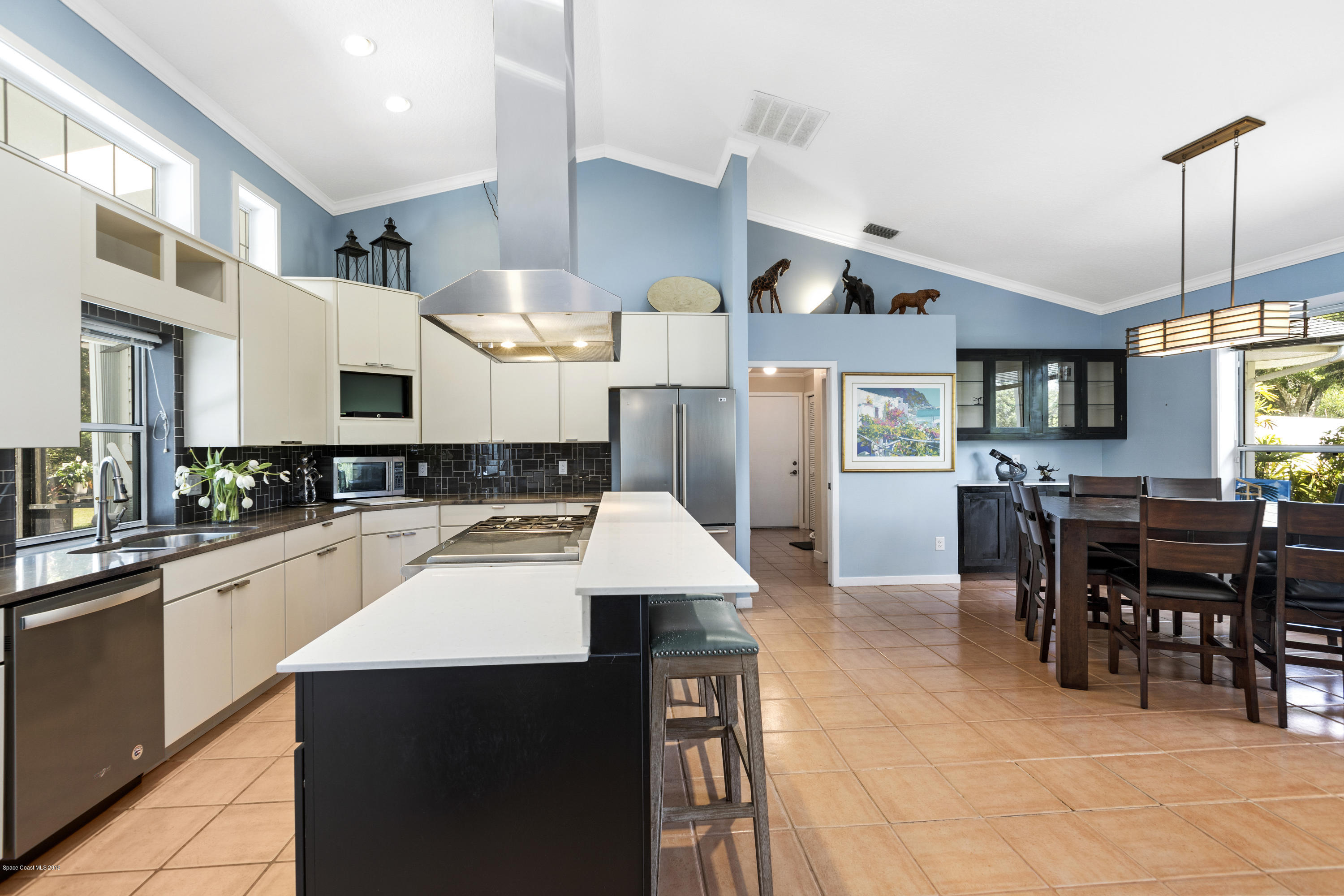 4231 Turtle Mound Road Melbourne, FL 32934 - Photo 3 of 39 a kitchen with stainless steel appliances kitchen island granite countertop a table chairs and a refrigerator