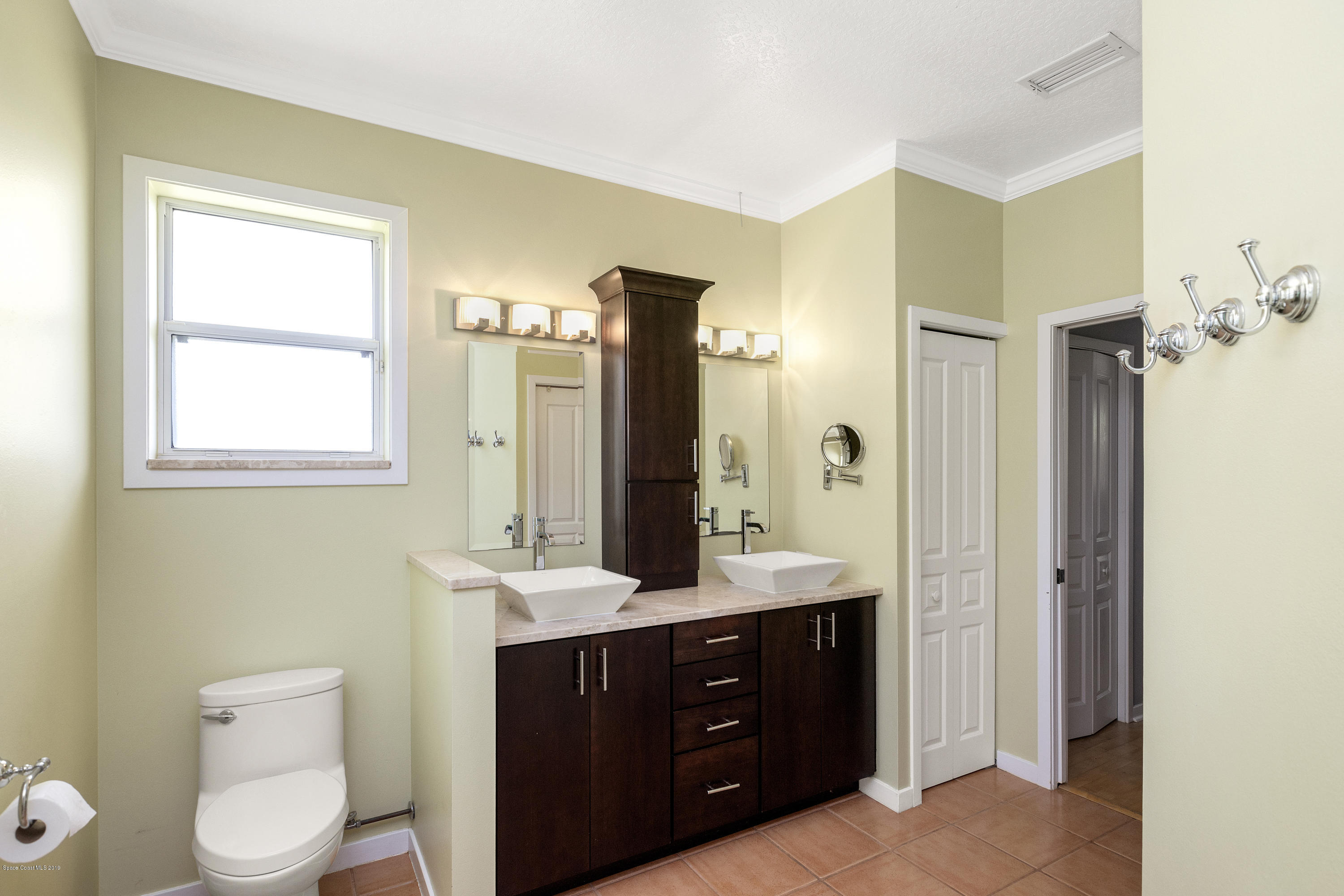 4231 Turtle Mound Road Melbourne, FL 32934 - Photo 23 of 39 a bathroom with a toilet a sink a mirror and vanity
