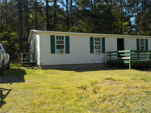 a view of house with yard and trees in the background