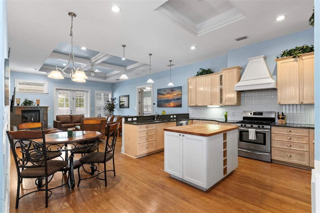 12080 143rd Street North Largo, FL 33774 - Photo 14 of 49 a kitchen with stainless steel appliances granite countertop a stove top oven a refrigerator a sink and a dining table with wooden floor