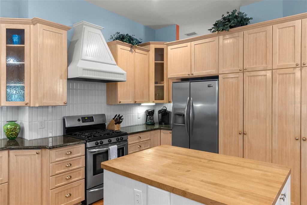 12080 143rd Street North Largo, FL 33774 - Photo 17 of 49 a kitchen with granite countertop a refrigerator a sink a stove and white cabinets