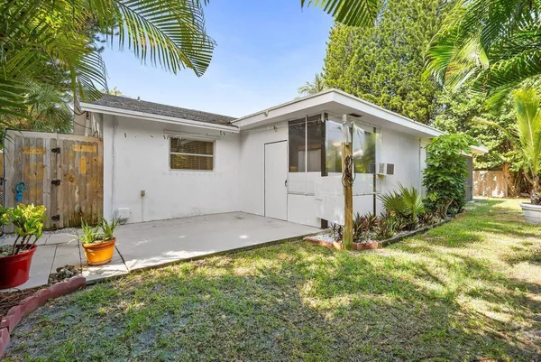 a backyard of a house with plants and large trees