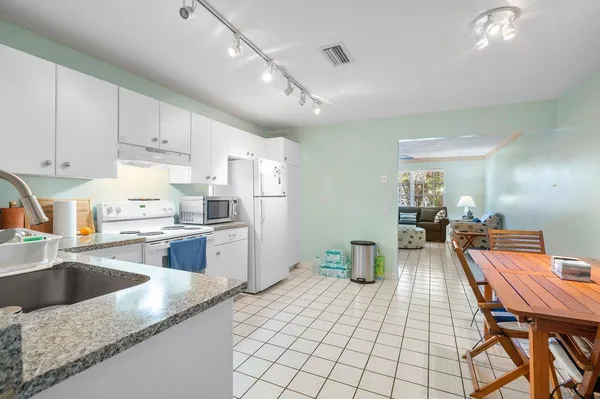 a kitchen with a sink dishwasher a stove a dining table and chairs with wooden floor