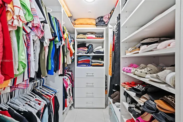 a view of walk in closet with clothes and shoes