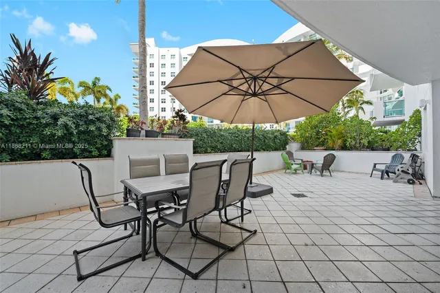a view of a patio with a table and chairs under an umbrella