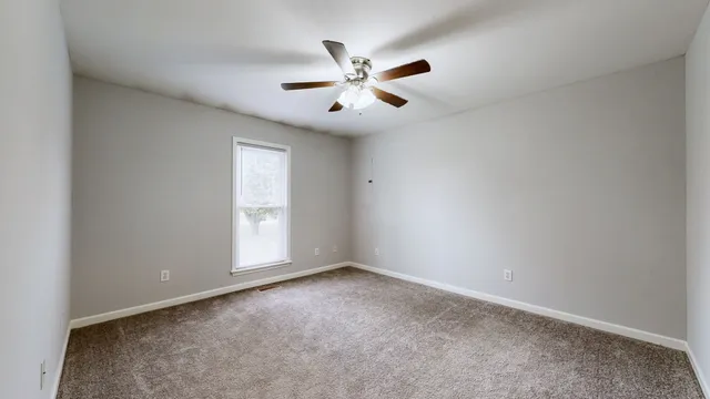 an empty room with window and ceiling fan