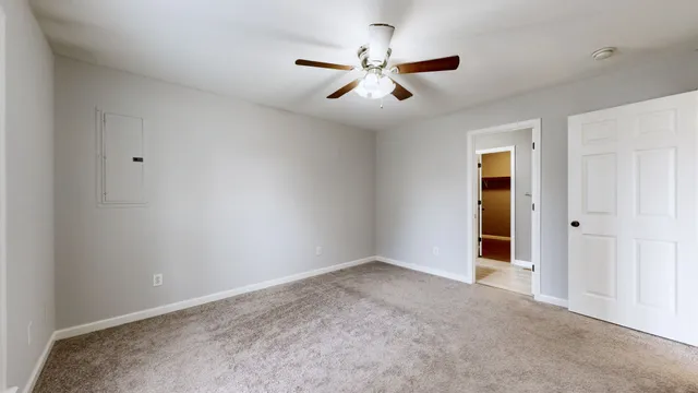a view of an empty room and chandelier fan