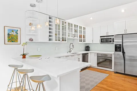 a kitchen with a sink a stove a refrigerator and chairs