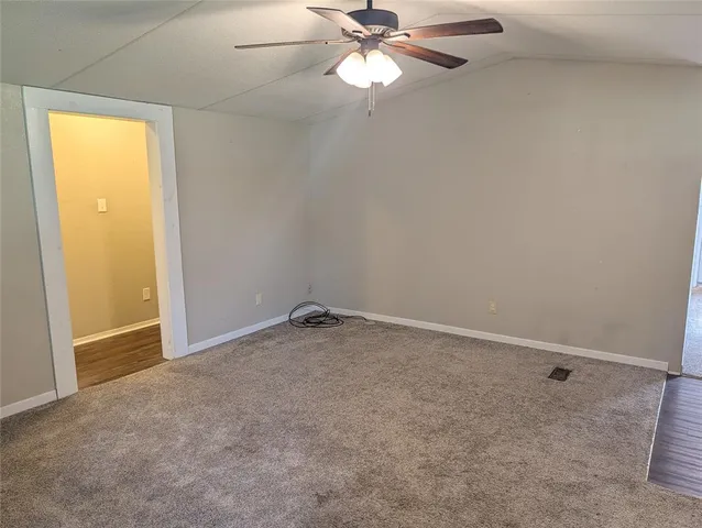 an empty room with a chandelier fan and windows