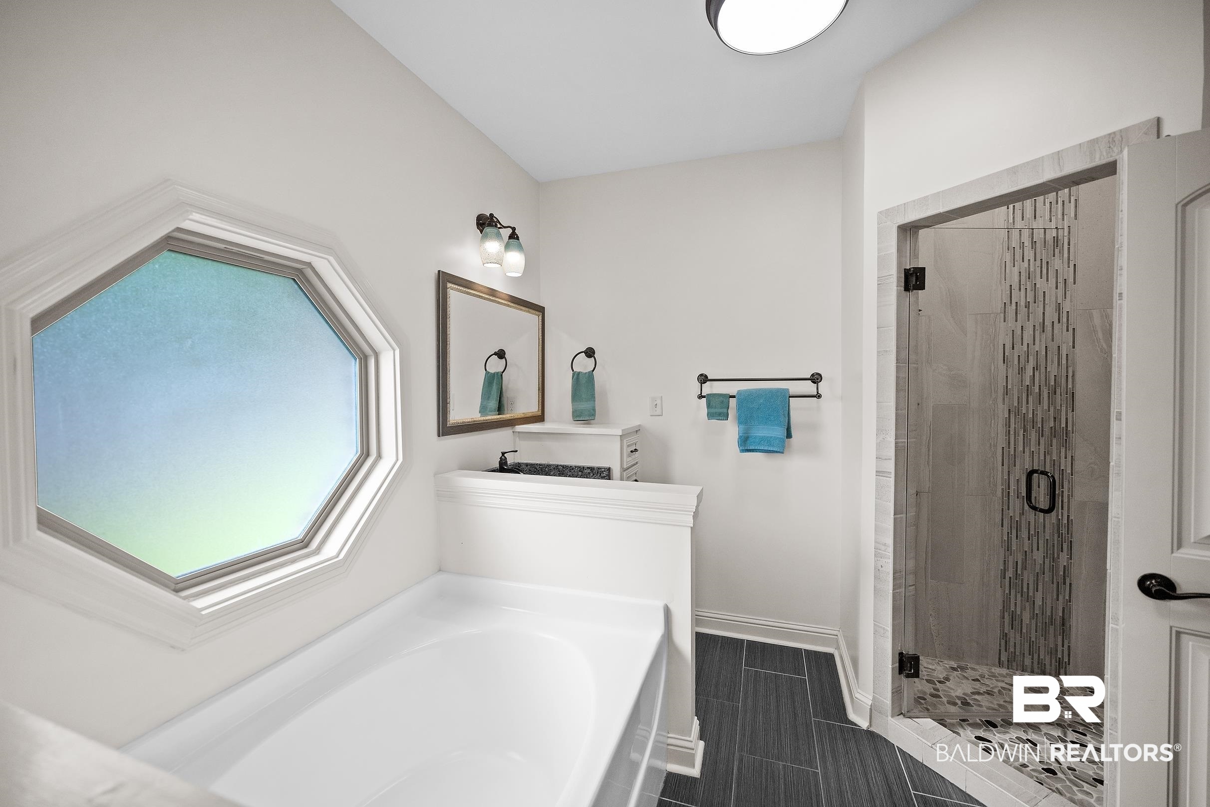 313 Pecan Ridge Boulevard Fairhope, AL 36532 - Photo 15 of 51 Modern bathroom featuring a soaking tub, octagonal window, and a glass-enclosed shower