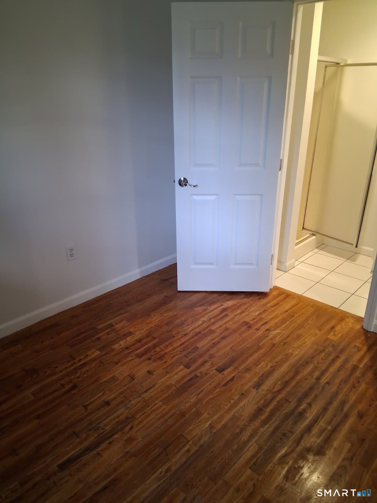 100 Mt Pleasant Street Derby, CT 06418 - Photo 3 of 6 an empty room with wooden floor and door