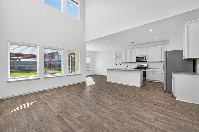 a view of kitchen with stainless steel appliances wooden floor and large window