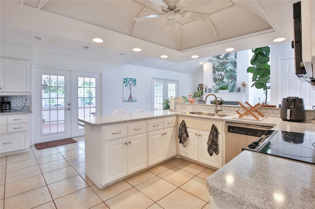 7303 Manatee Street Sarasota, FL 34243 - Photo 14 of 39 a large white kitchen with a stove a sink a dining table and chair with wooden floor