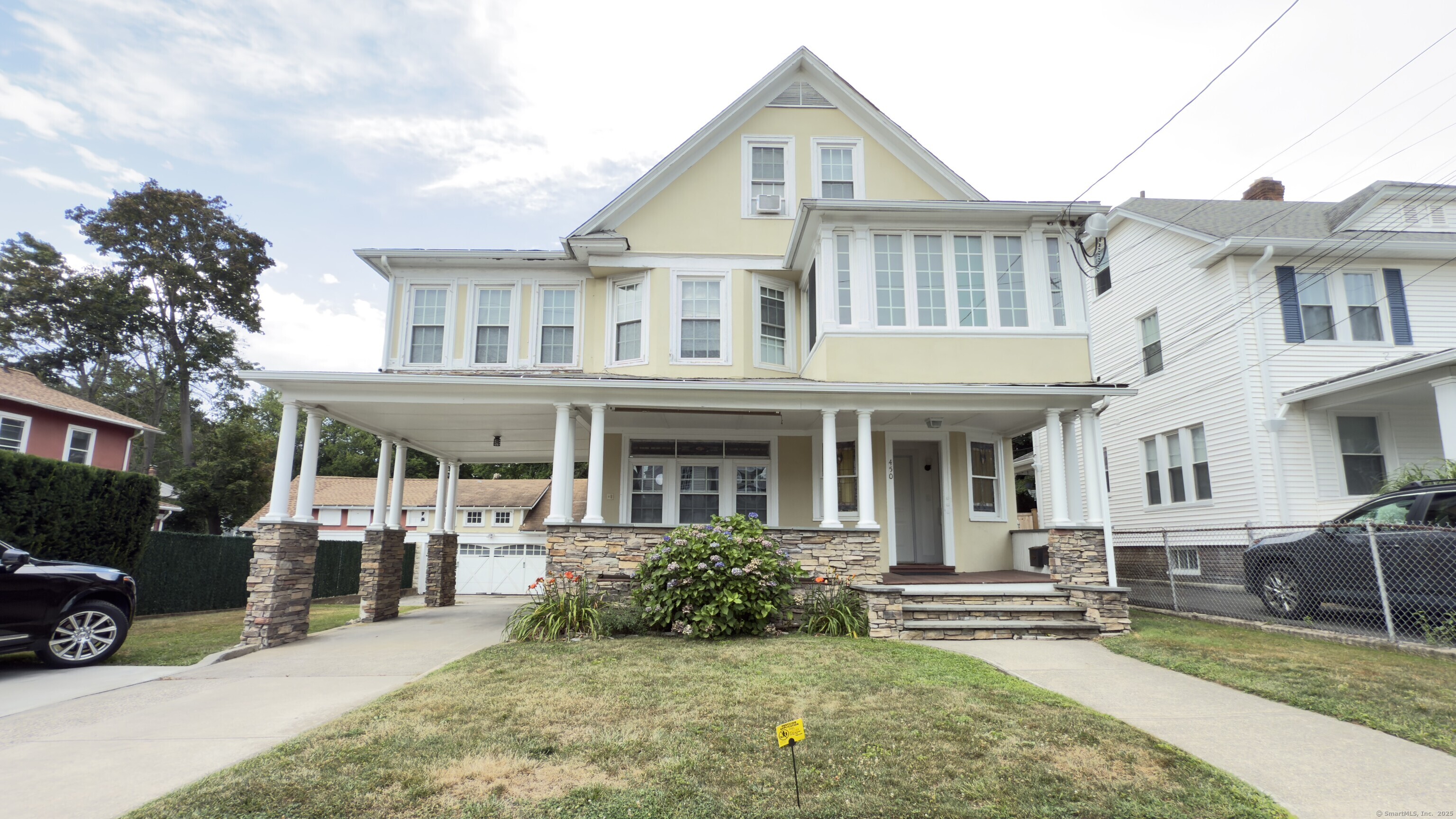 450 Davidson Street Bridgeport, CT 06605 - Photo 1 of 16 a view of a white house with large windows and a table and chairs under an umbrella