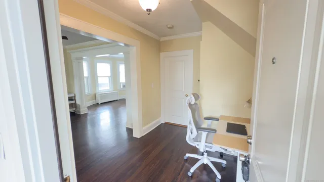 a view of a hallway with wooden floor table and chairs