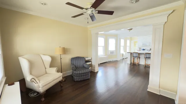 a living room with couches chairs and a dining table with wooden floor
