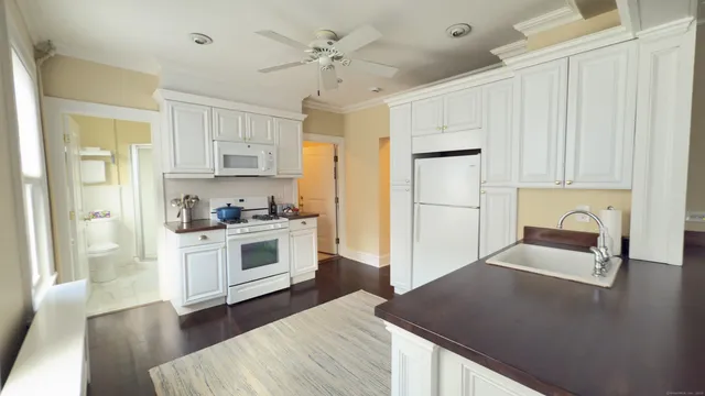 a kitchen with granite countertop white cabinets and white appliances