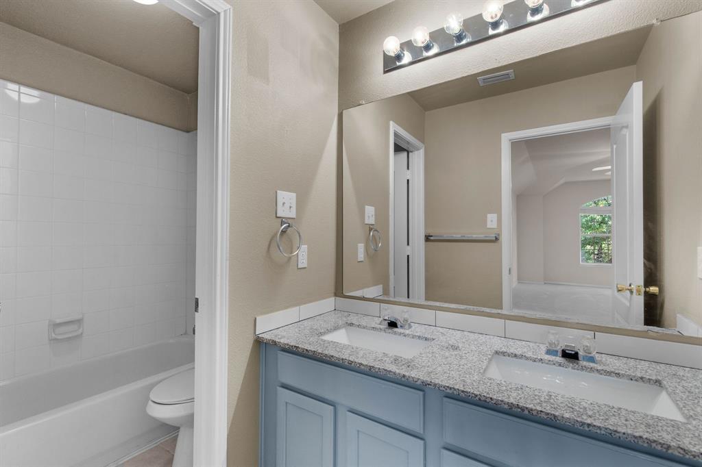 2700 Hereford Road Denton, TX 76210 - Photo 23 of 36 Bathroom featuring a double vanity with light blue cabinetry, dual undermount sinks, and a speckled countertop