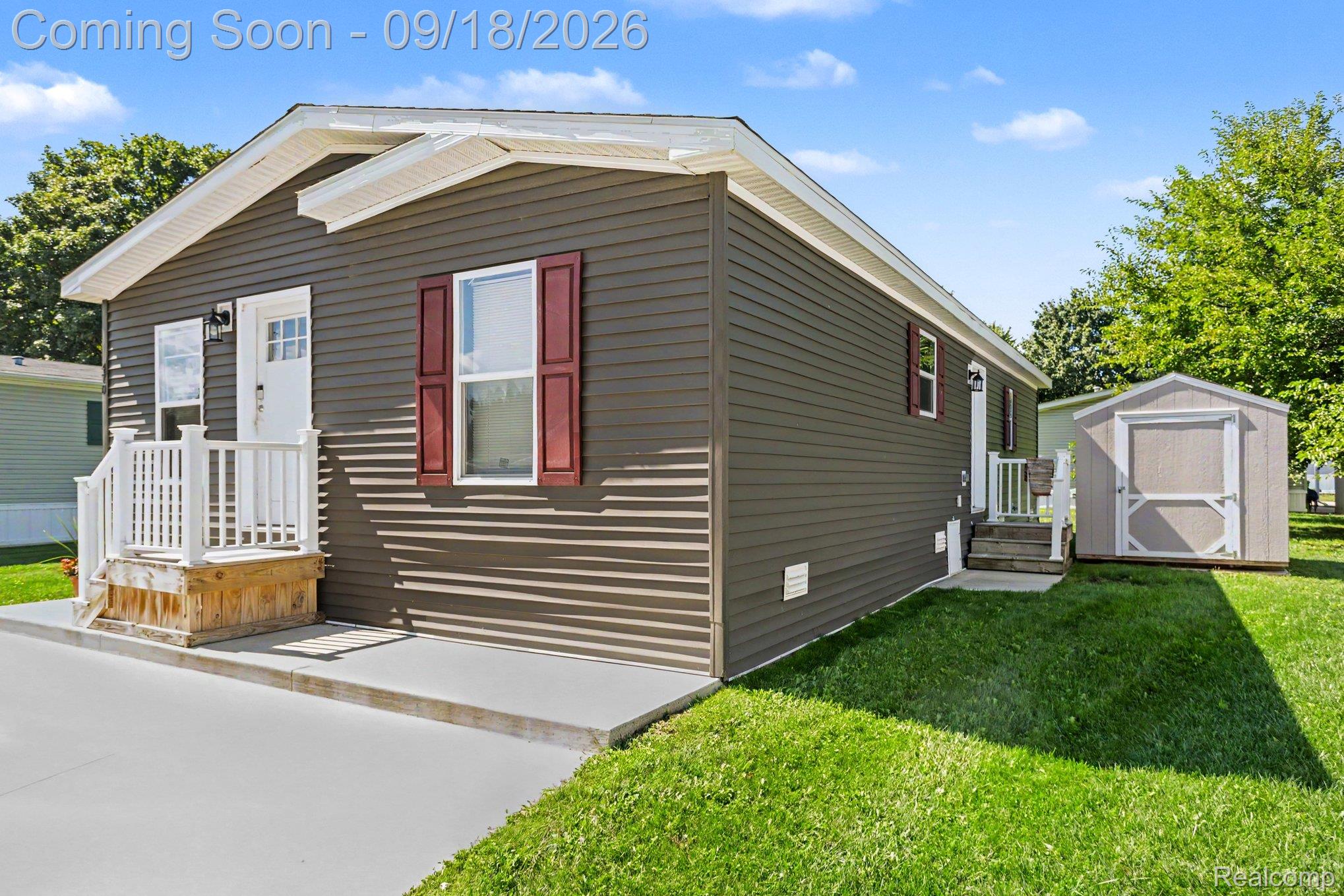 470 Flamingo Street Rochester, MI 48309 - Photo 14 of 17 Dark siding exterior with white trim, front entry porch with white railing, concrete driveway, and a detached shed