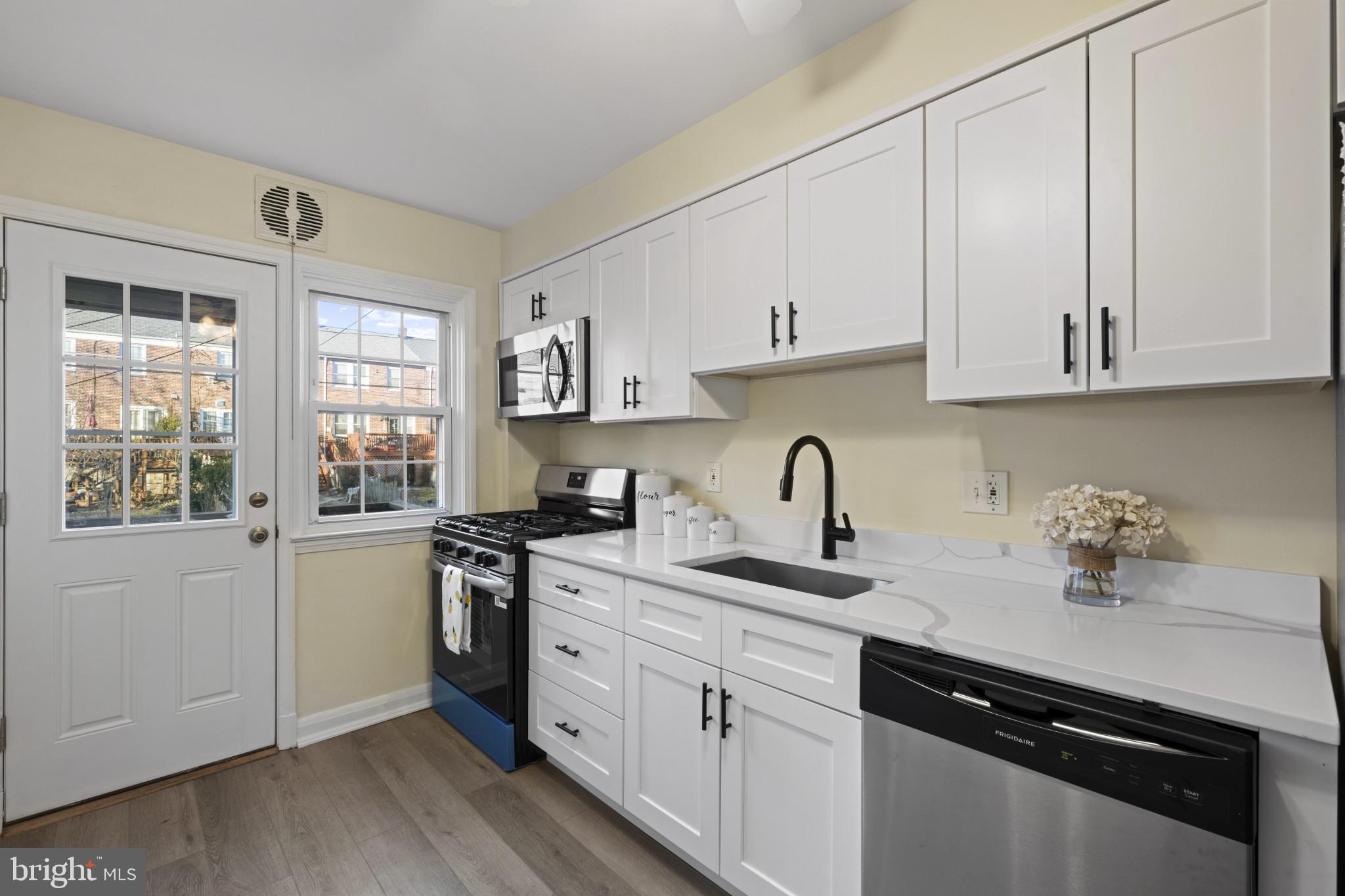 132 Overbrook Road Baltimore, MD 21212 - Photo 13 of 36 a kitchen with stainless steel appliances granite countertop a sink dishwasher stove and white cabinets with wooden floor