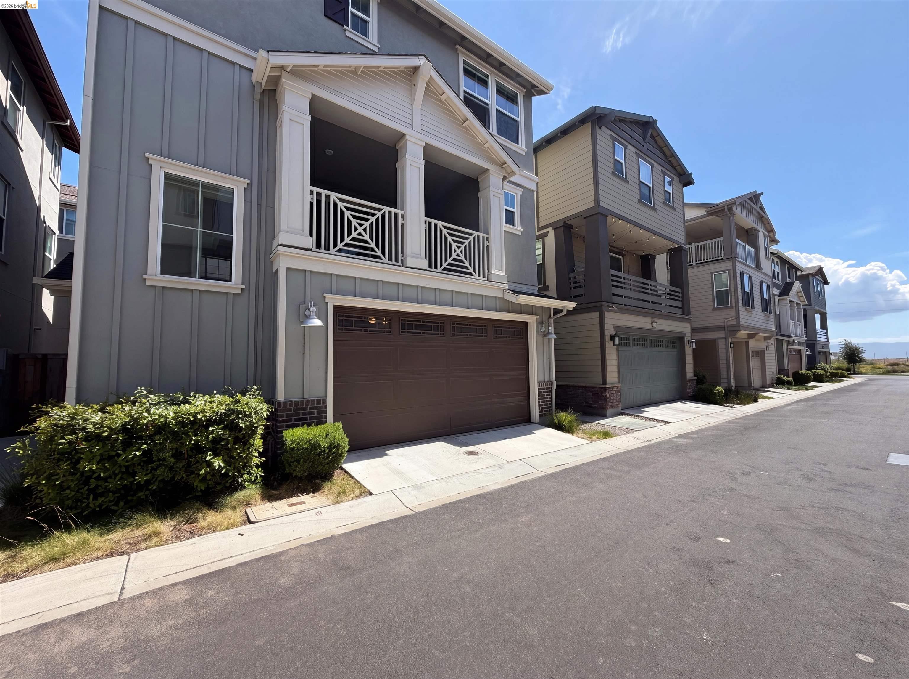 9034 Rudder Way Newark, CA 94560 - Photo 36 of 38 Contemporary multi-level residence featuring board and batten siding, a prominent balcony with decorative railing, and an integrated garage with a paneled door